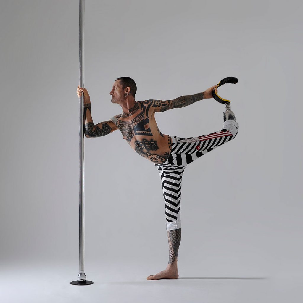 male pole dancing teacher in entry level pole sport pose in class at london dance academy